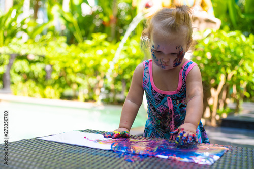 happy baby child draws with colored paints hands.