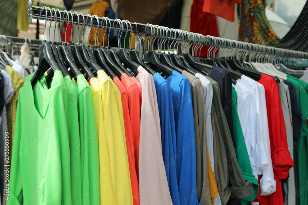 clothes stand at the market with many colored cotton t-shirts