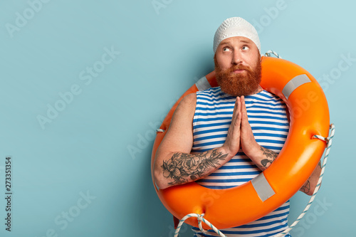 Fototapet Hopeful handsome male swimmer keeps palms pressed together, prays for safe swimm