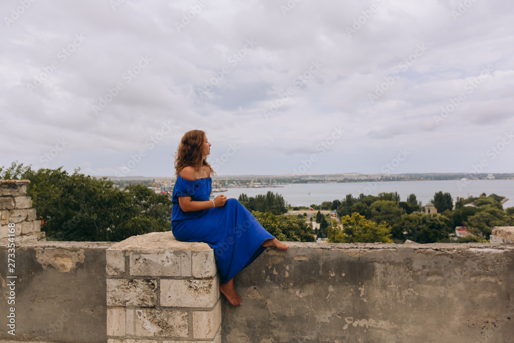 Fototapeta premium Beautiful tanned girl in long blue dress