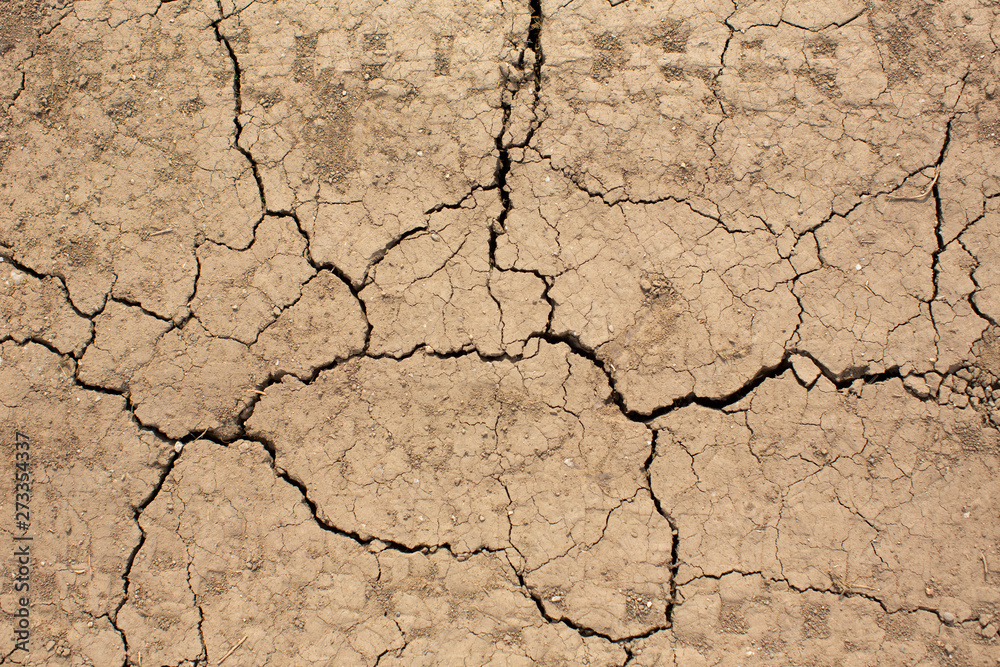 Cracked earth on country road with traces of tires. Texture background of dry cracked earth. Cracked earth on country road with traces of tires. Texture background of dry cracked earth.