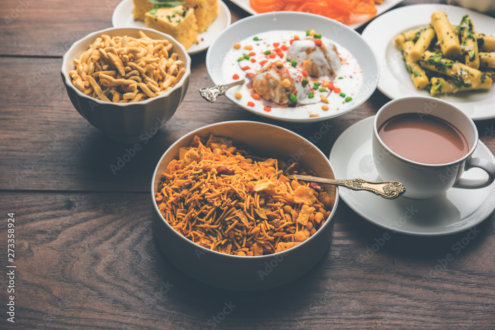 Group of Gujarati snacks like jalebi-fafda, thepla, khaman dhokla, aloo bhujiya, khandvi,khakra, dahi vada, gathiya with hot tea