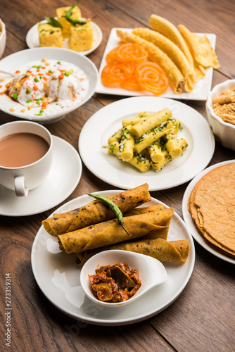 Group of Gujarati snacks like jalebi-fafda, thepla, khaman dhokla, aloo bhujiya, khandvi,khakra, dahi vada, gathiya with hot tea