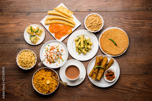 Group of Gujarati snacks like jalebi-fafda, thepla, khaman dhokla, aloo bhujiya, khandvi,khakra, dahi vada, gathiya with hot tea photo