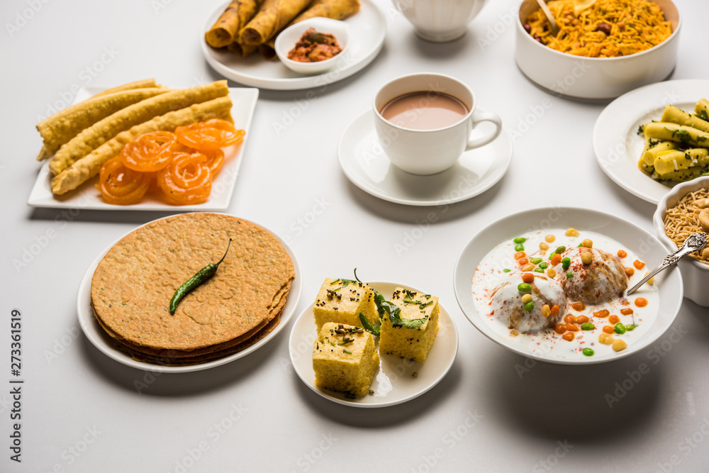 Group of Gujarati snacks like jalebi-fafda, thepla, khaman dhokla, aloo bhujiya, khandvi,khakra, dahi vada, gathiya with hot tea