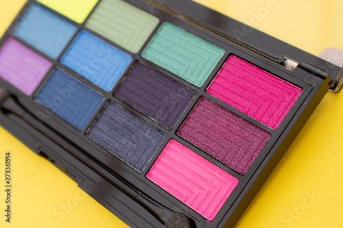 Colorful eyeshadow palette on yellow background