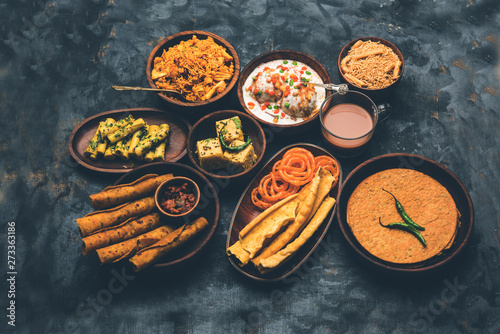 Group of Gujarati snacks like jalebi-fafda, thepla, khaman dhokla, aloo bhujiya, khandvi,khakra, dahi vada, gathiya with hot tea photo