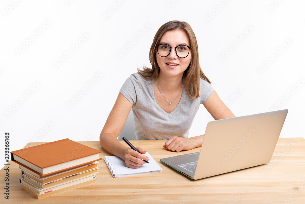 People and education concept - Happy female student sitting at the wooden table with laptop People and education concept - Happy female student sitting at the wooden table with laptop