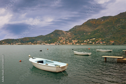 Cloudy autumn landscape - mountains, sea, and fishing boats on the water. Montenegro, Adriatic Sea, view of Bay of Kotor near Verige Strait