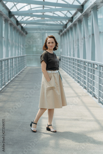 Free Download Beautiful stylish woman with backpack, smiling, happy, street style, beige skirt, green t-shirt. - GFXLoad