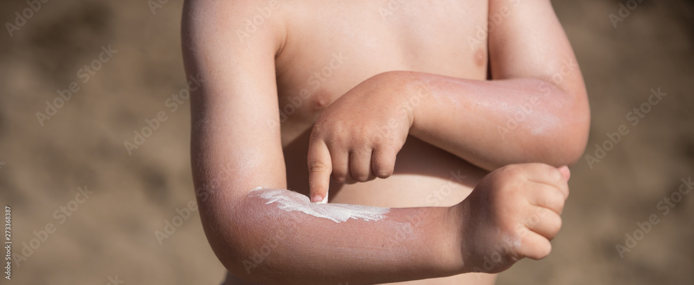 Suntan cream. Protect children skin from the sun in the summer. Boy puts cream on his hand. Skin care.