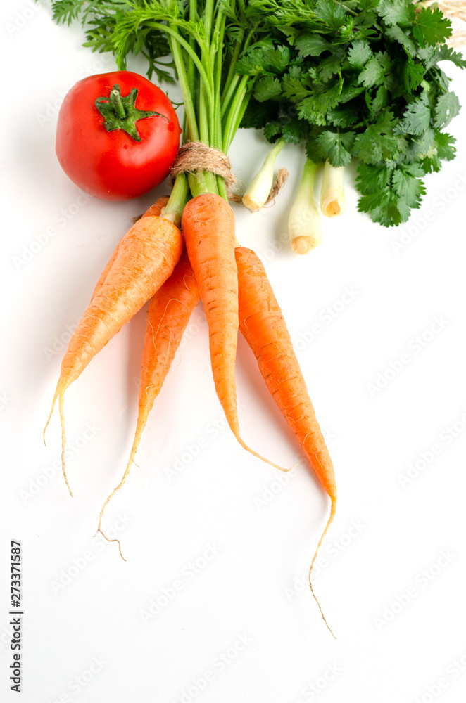 Fresh carrot with green leaves, tomato, onion and parsley on white background. Fresh carrot with green leaves, tomato, onion and parsley on white background.