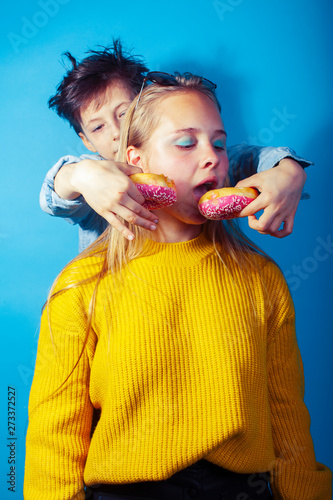happy family brother and sister eating donuts on blue background, lifestyle people concept, boy and girl eating unhealthy