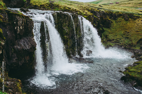 Fototapeta Naklejka Na Ścianę i Meble -  The waterfall of Kirkjufell in Iceland. Clear water falling into the stream. Beautiful scenery on a cold grey afternoon.