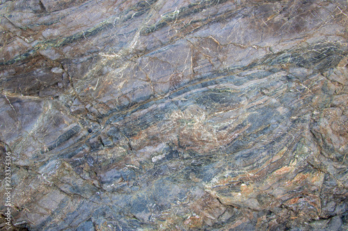 A rock blended with greyish blue, brown, and white colours and a combination of soft and hard textures.