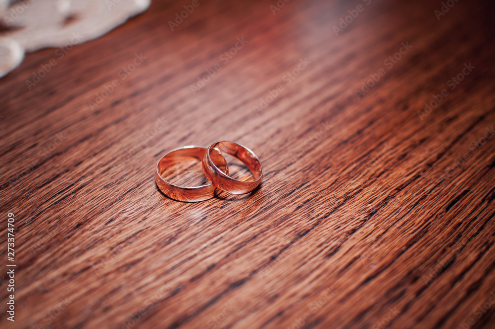 Pair of gold wedding rings on the wooden table Pair of gold wedding rings on the wooden table