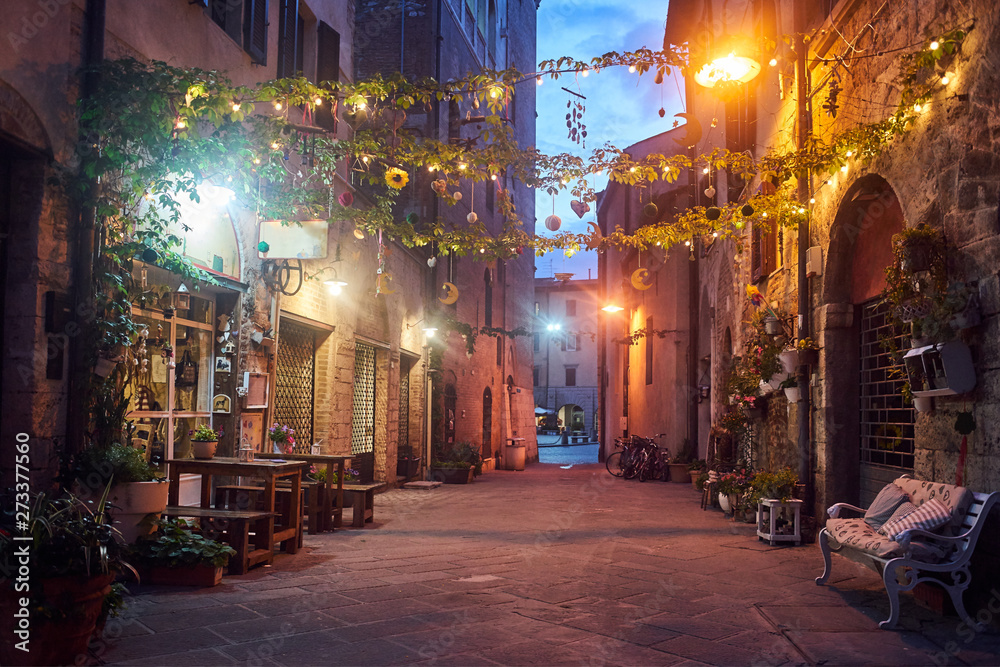 Cafes in a narrow street in the evening in the city of Grosseto, Italy.