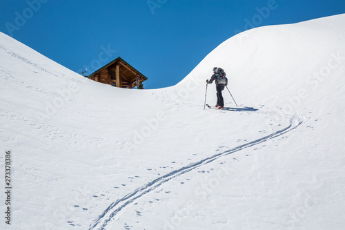 Skier skinning uphill, hiking toward a backcountry ski hut in the Rocky Mountains of British Columbia, Canada.