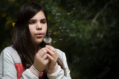 Young beautiful Girl blowing dandelion flower