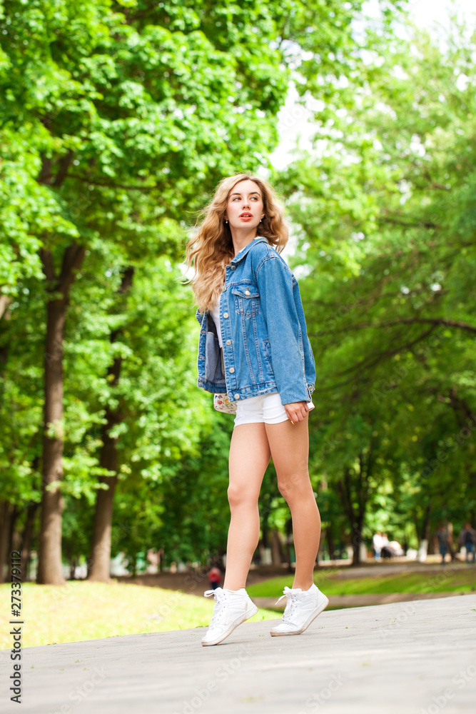 Beautiful sexy blonde woman dressed in a denim jacket and shorts