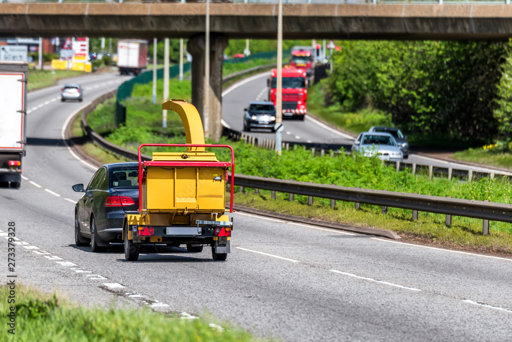 wood chipper towed by car on uk motorway in fast motion