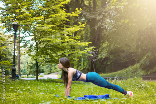 Yoga outdoor. Happy woman doing yoga exercises, meditate in the park. Yoga meditation in nature. Concept of healthy lifestyle and relaxation. Pretty woman practicing yoga on the grass © MartaKlos