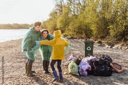 Family of enthusiasts doing voluntary Saturday work, picking garbage near river.