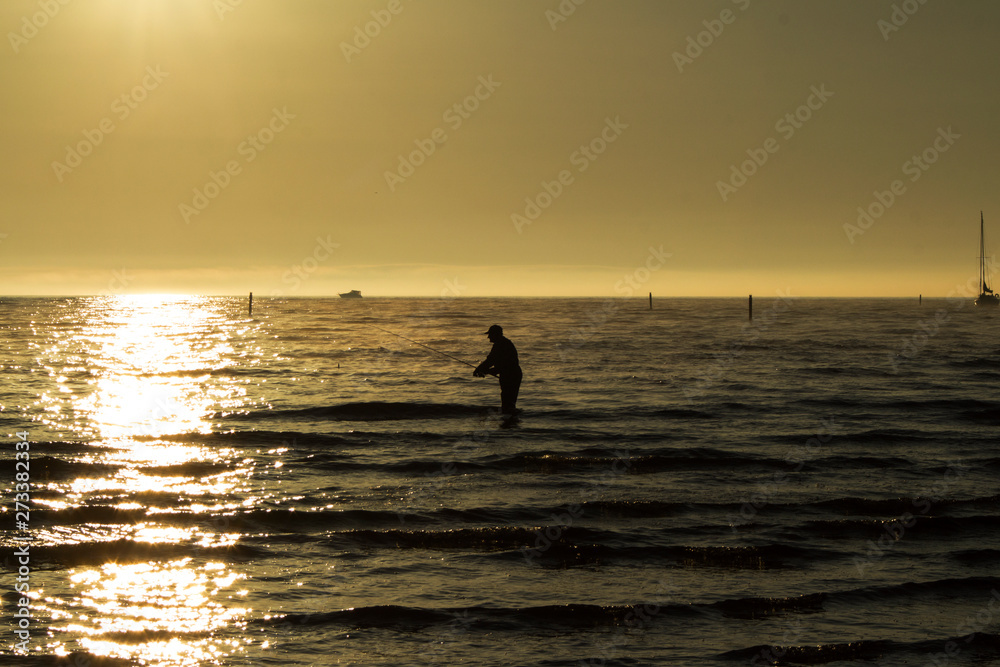 silhouette of a fisherman with a fishing rod in the sea