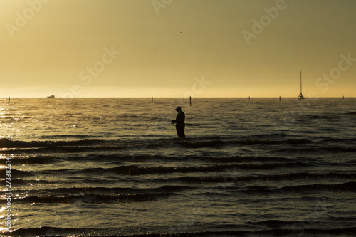 silhouette of a fisherman with a fishing rod in the sea