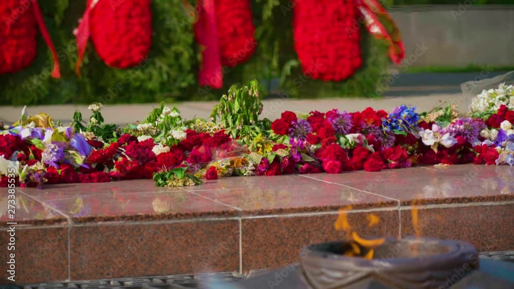 Red and white funeral flowers with ribbon on the Eternal Flame memorial monument at Tomb of Unknown Soldier - symbol of victory in World War II and memory of millions victims people defenders the moth