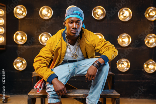 Картината върху платно Black rapper in cap sitting on the steps