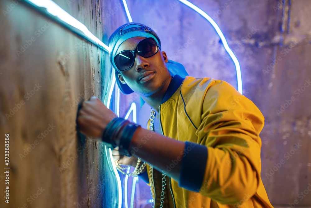 Black rapper in underpass neon light on background - obrazy, fototapety, plakaty 