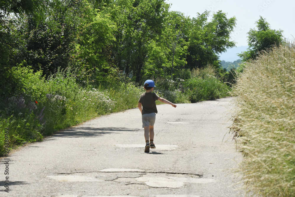 Child running in the street. Little boy running on the middle of the road. Boy on the street