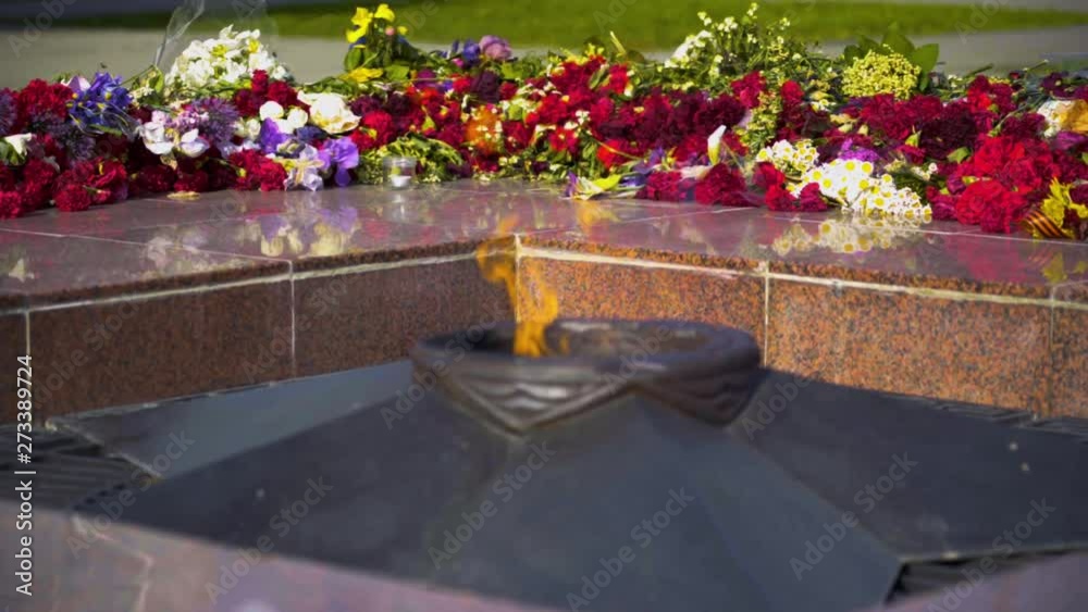 Red and white funeral flowers with ribbon on the Eternal Flame memorial monument at Tomb of Unknown Soldier - symbol of victory in World War II and memory of millions victims people defenders the moth