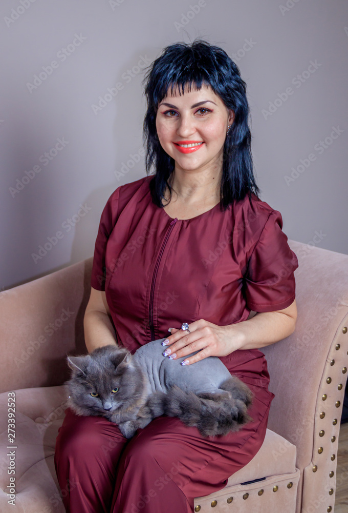 Obraz premium A woman in a medical suit with a cat. Woman doctor with a cat. Gray cat.