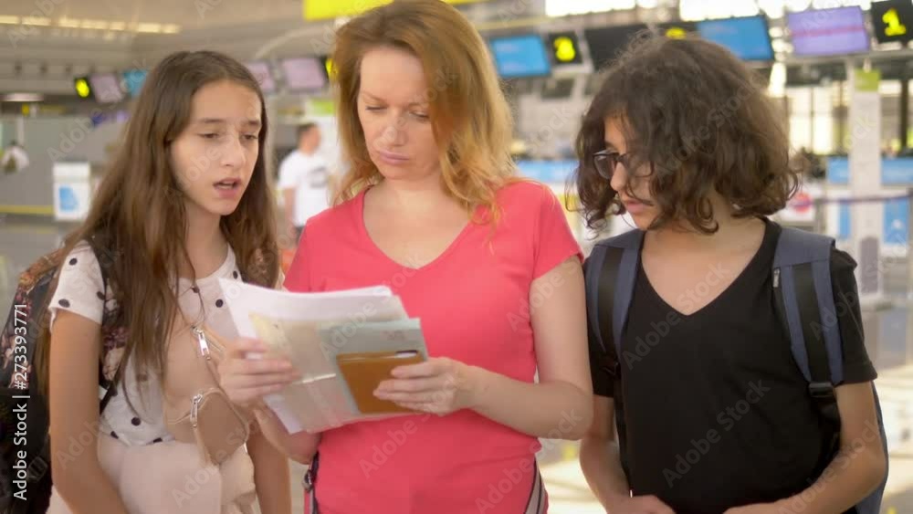 concept of tourism, vacation and exchange training. A woman and two teenagers, a boy and a girl, are standing at the airport at the ticket office for flight check-in. concept of tourism, vacation and exchange training. A woman and two teenagers, a boy and a girl, are standing at the airport at the ticket office for flight check-in.