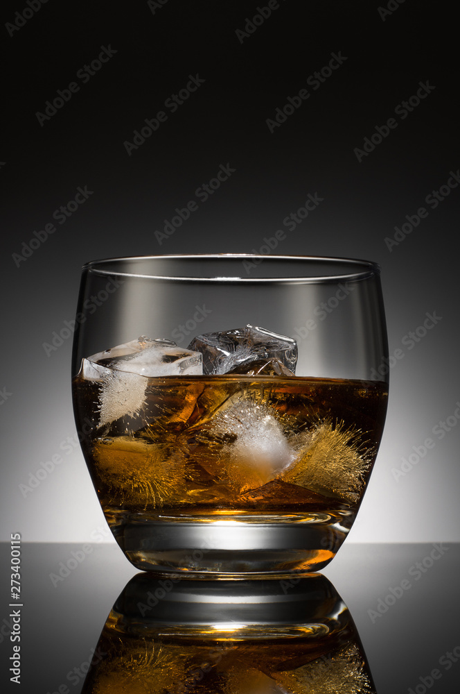 Whiskey with ice cubes in a glass on the background of a round black & white gradient Whiskey with ice cubes in a glass on the background of a round black & white gradient