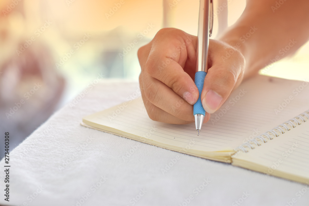Close-up of male hand with pen writing on a notebook. Close-up of male hand with pen writing on a notebook.