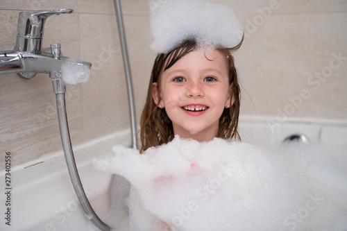 little girl in bath playing with foam
