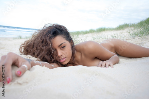 A sexy brunette sleeping on beach in sand