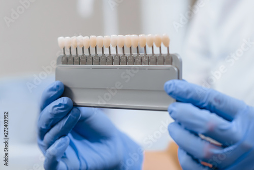 Teeth whitening. A device for assessing the color of tooth enamel in the hands of a dentist. Close-up.