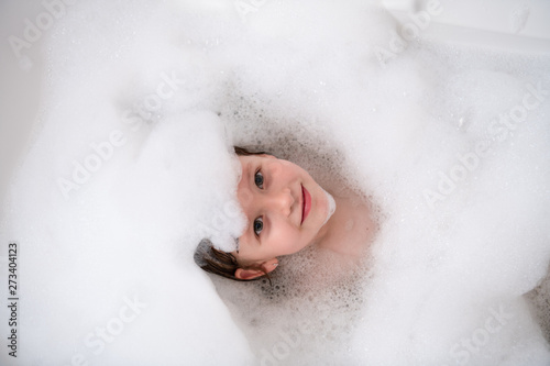 top view of little girl in bath playing with foam