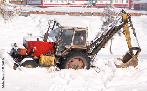 Tractor in the snow. Winter rural scene.