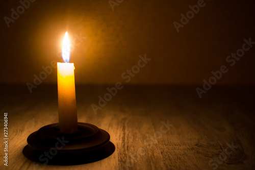 Burning candle on wooden table. Candle light in the dark