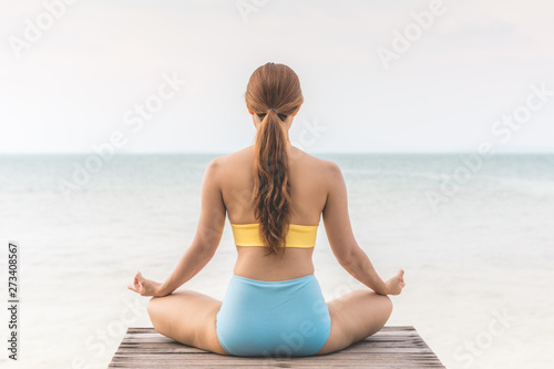 Back of views woman practice yoga lotus pose to meditation summer vacation on pier with sea beach feeling so happiness and cheerful Travel in tropical beach Thailand vacations and relaxation Concept