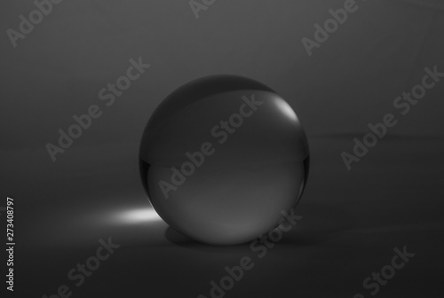 Crystal glass ball sphere transparent on dark grey gradient background.