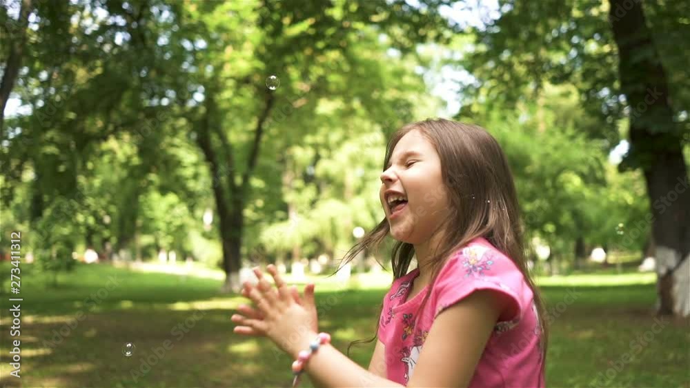 Smiling child girl play with soap bubbles in summer city park. Slow motion, happy childhood emotion, steady shot Smiling child girl play with soap bubbles in summer city park. Slow motion, happy childhood emotion, steady shot
