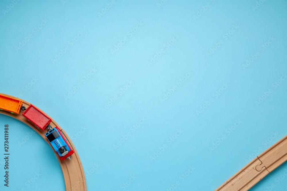 Children's railway with wooden rails on a blue background, top view. Copy space for text.