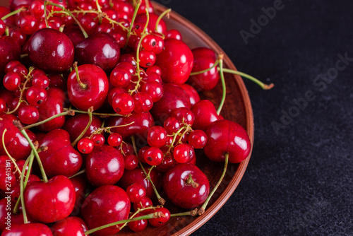 Sweet fresh organic cherry background close-up. Cherry in the plate with leaves on a dark background