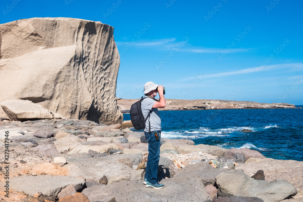 Senior people enjoying the view over the sea looking with a binoculars. Blue sky and water in background. Large white cliff. Vacation for a retired person Senior people enjoying the view over the sea looking with a binoculars. Blue sky and water in background. Large white cliff. Vacation for a retired person